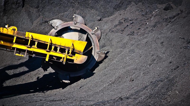 A bulldozer digging into a pile of coal.