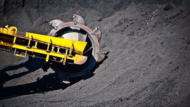 A bulldozer digging into a pile of coal.