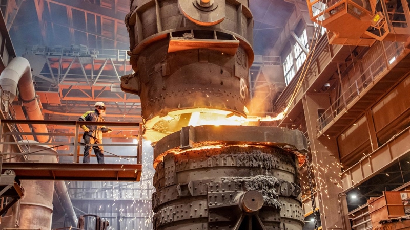 A worker is smelting metal on a raise platform in an industrial factory.