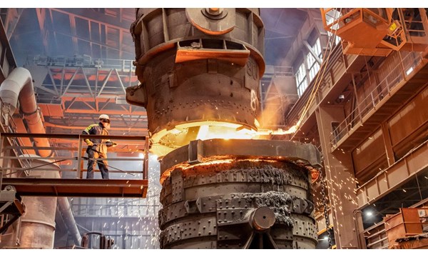 A worker is smelting metal on a raise platform in an industrial factory.