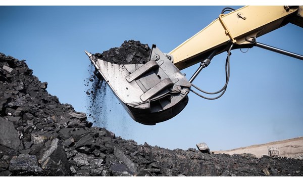An excavator is scooping coal out of a pile.