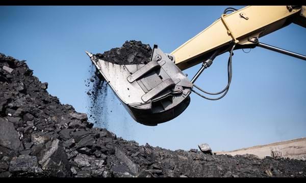An excavator is scooping coal out of a pile.