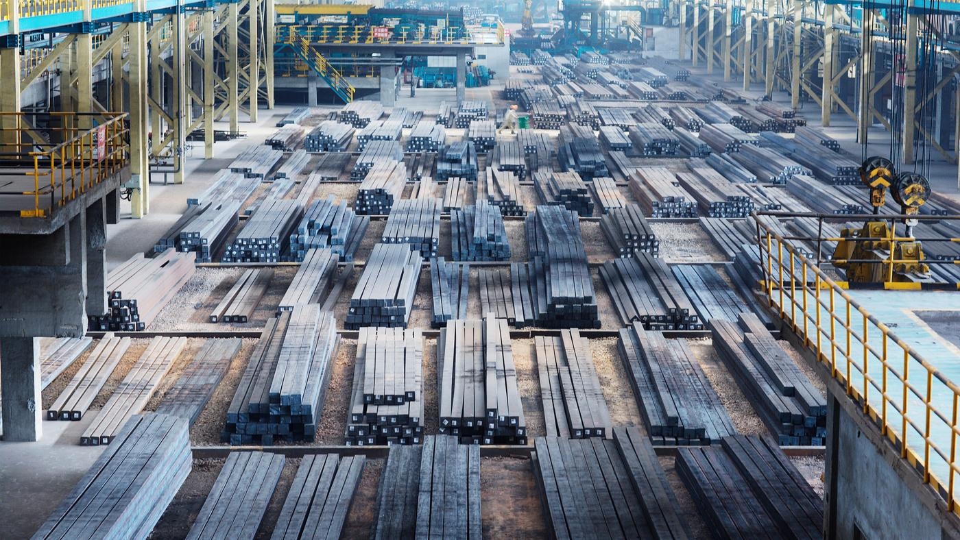 A large open factory with vast amounts of steel beams lined up.