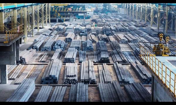 A large open factory with vast amounts of steel beams lined up.