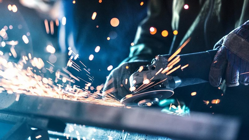 A worker is grinding metal with sparks.
