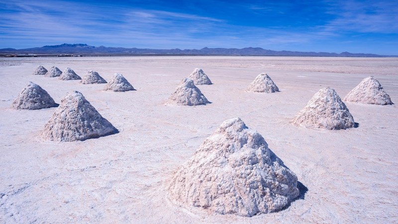 Several large cone-shaped piles of lithium deposits in the middle of a salt flat.