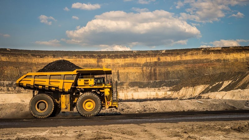 A large truck carrying coal driving through a mine.