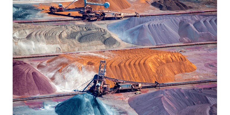 Two large excavators working piles of rocks.