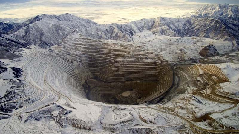 A vast, deep quarry in the middle of a mountain range.