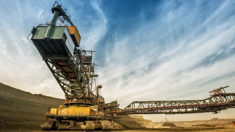 A large crane is in the middle of a quarry/mine, against a blue sky.