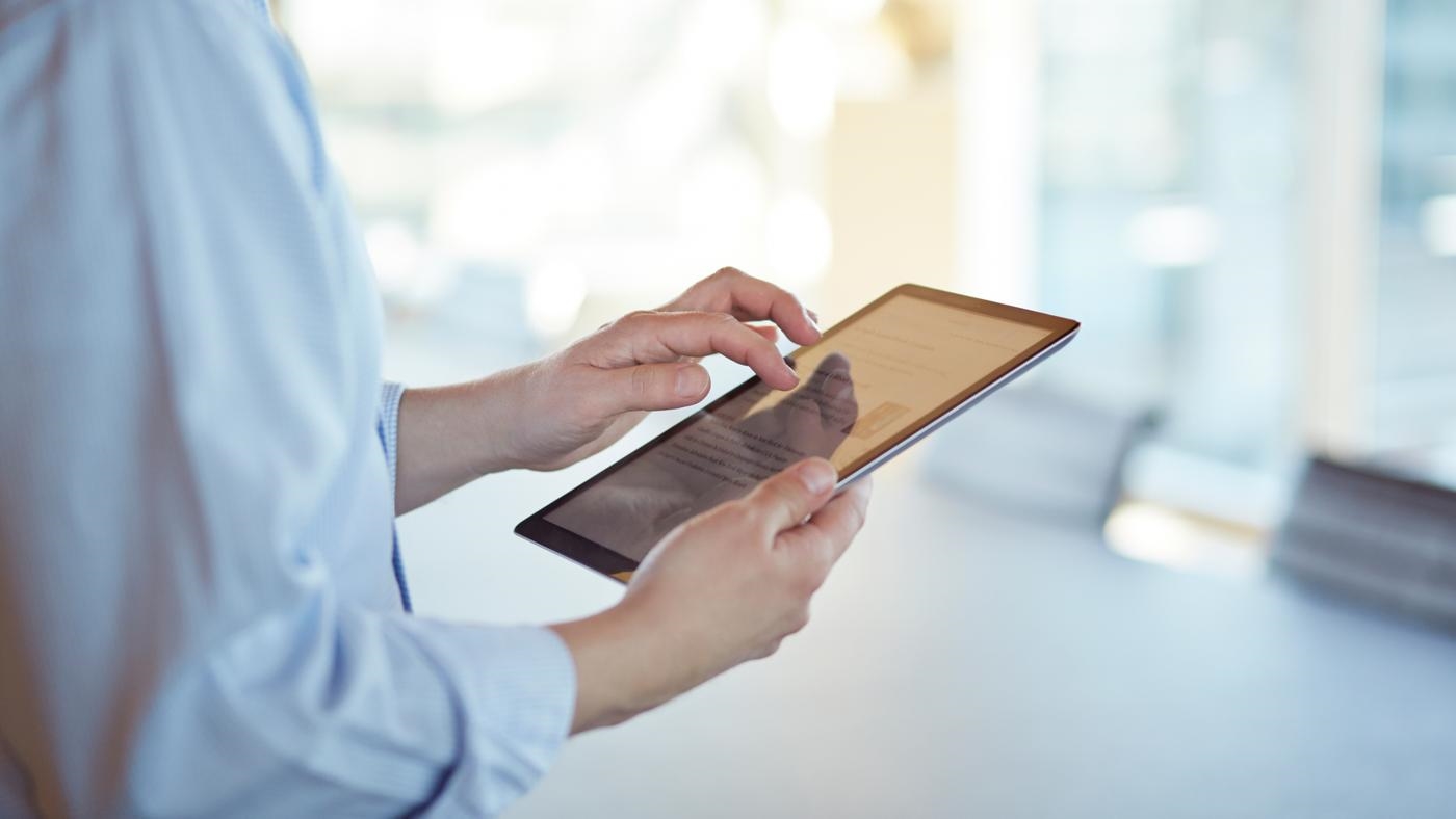 Corporate business still-life, in high-end office environment. Person using an iPad.