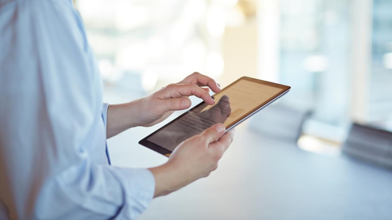 Corporate business still-life, in high-end office environment. Person using an iPad.