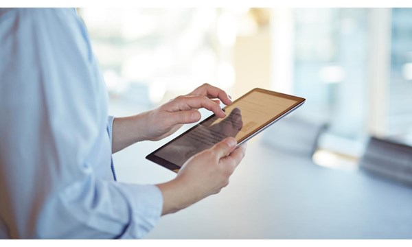 Corporate business still-life, in high-end office environment. Person using an iPad.