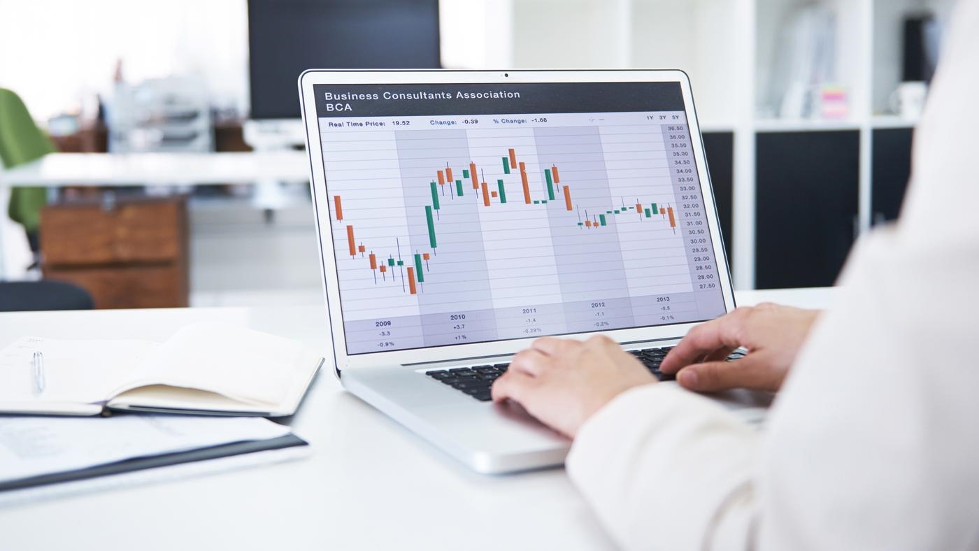 Rearview shot of a  businesswoman working with financial graphs on her laptop, in an office environment.