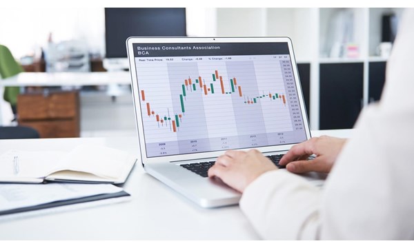 Rearview shot of a  businesswoman working with financial graphs on her laptop, in an office environment.