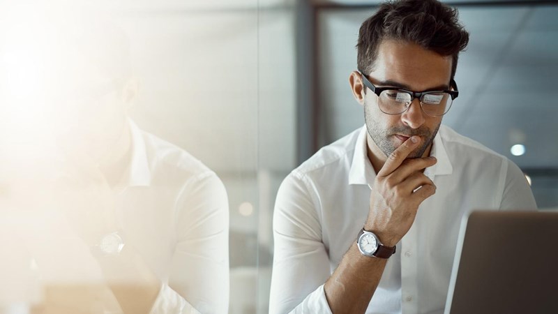 Cropped shot of a young businessman, looking thoughtful while working on his laptop in the office.