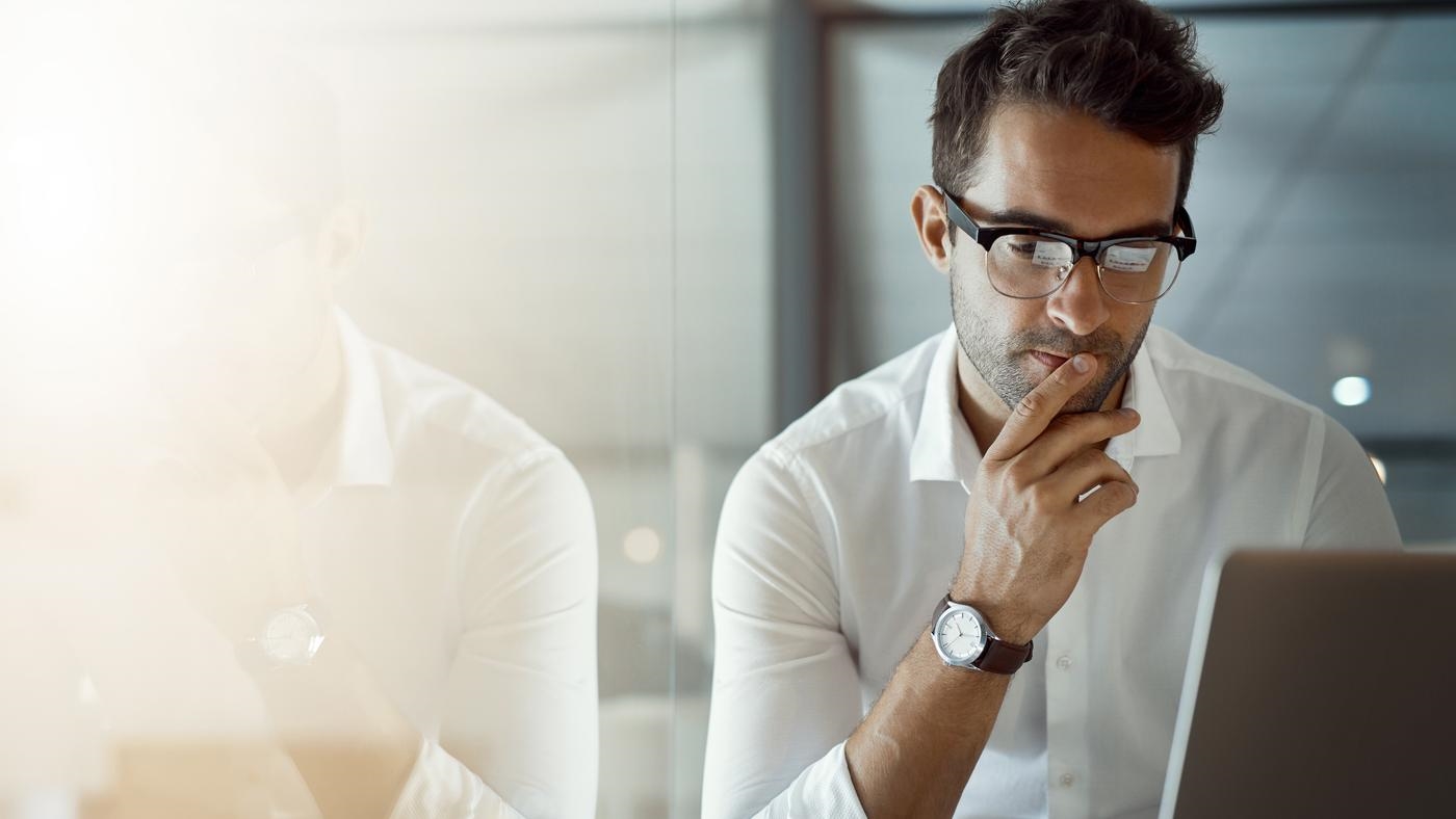 Cropped shot of a young businessman, looking thoughtful while working on his laptop in the office.