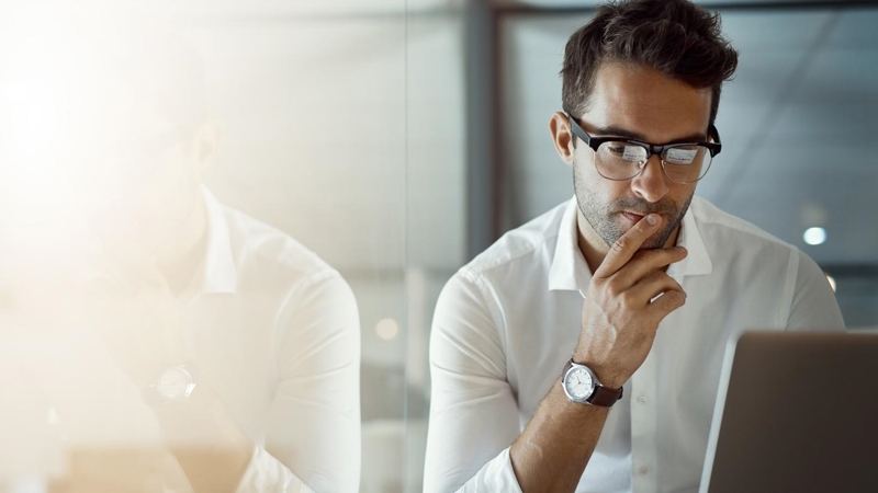 Cropped shot of a young businessman, looking thoughtful while working on his laptop in the office.