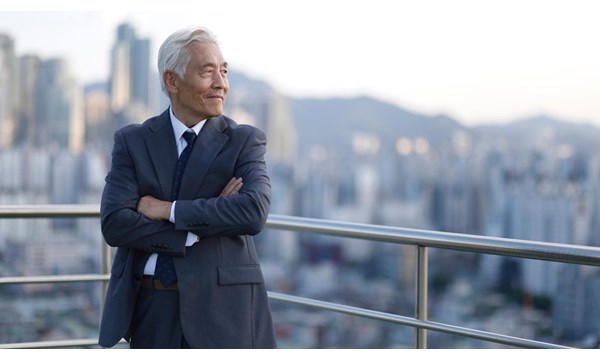 A man in a suit is standing on a balcony overlooking a city.