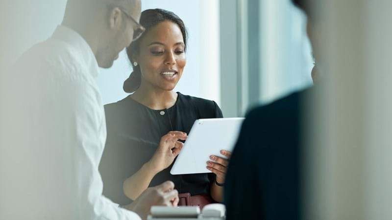Business people working in high-end modern office, a woman is using her iPad and smiling.