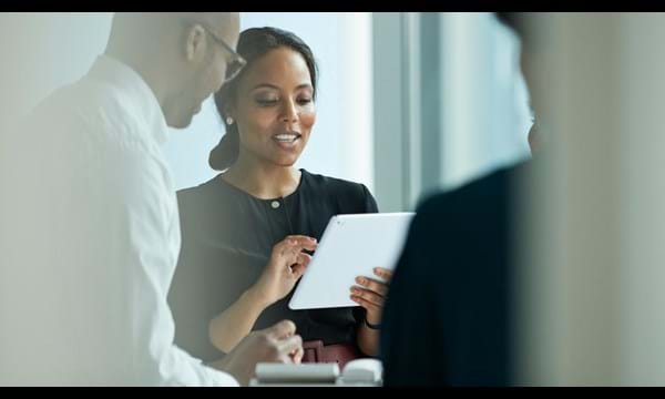 Business people working in high-end modern office, a woman is using her iPad and smiling.