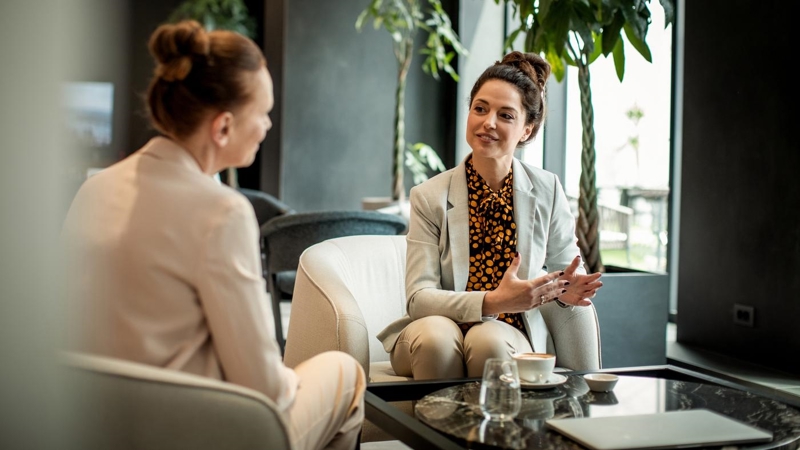 Close up of two businesswoman having coffee in an office lobby.