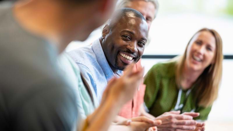 A close-up of a group of managers in a meeting in their offices in Hexham in the North East of England. They are doing ice breakers and introductions as they get to know each other before the meeting starts.