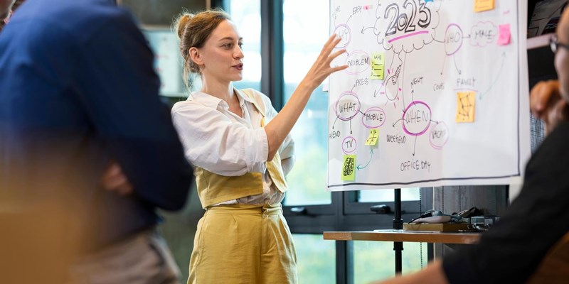 Empower Your Teams to Work Together More Effectively. A Female Business team leader present on new business workflows with her team for brainstorm ideas to manage customer project.