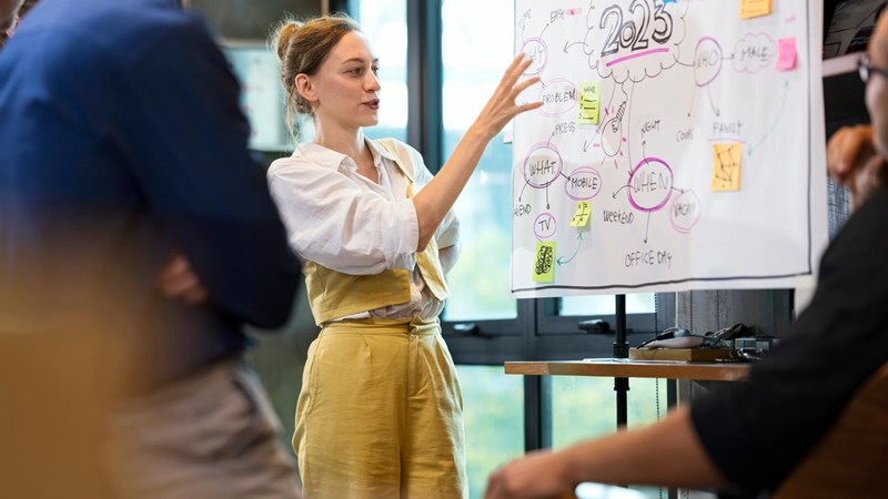 Empower Your Teams to Work Together More Effectively. A Female Business team leader present on new business workflows with her team for brainstorm ideas to manage customer project.