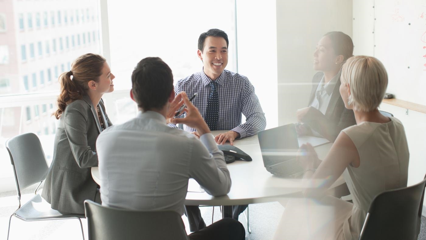 A group of business people are all smiling and having a meeting in a conference room.