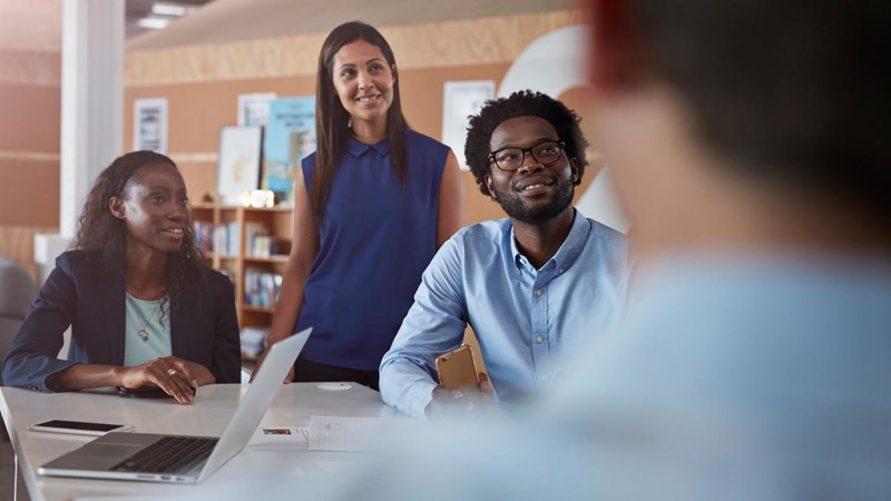 Businesspeople at creative agency, smiling during their meeting.