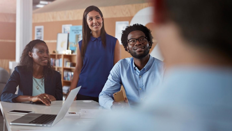 Businesspeople at creative agency, smiling during their meeting.