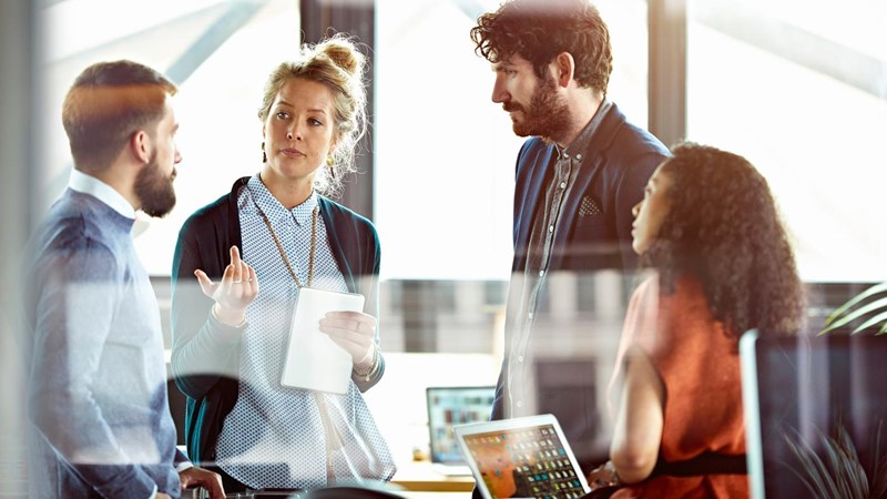 A group of men and women talking in modern office meeting room.
