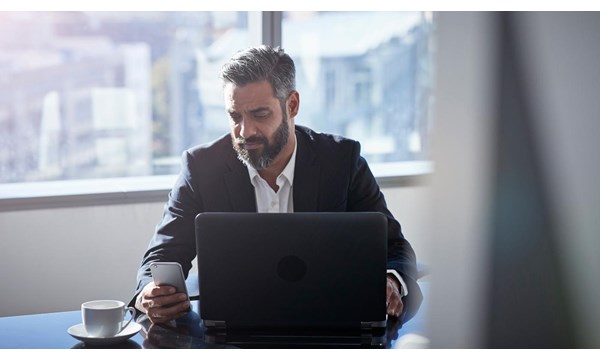 Modern chic business people working in an incredible modern & original office space. A man uses his smartphone and laptop.