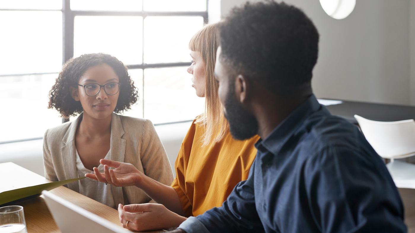 Businesswoman discussing strategy with male and female colleagues in modern office.