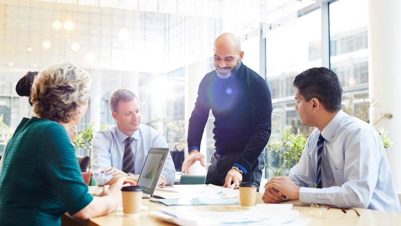A group of business people having a meeting around a table, in a large modern meeting room.