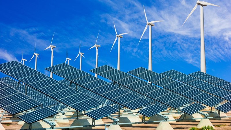 Solar panels and wind turbines in front of a blue sky.