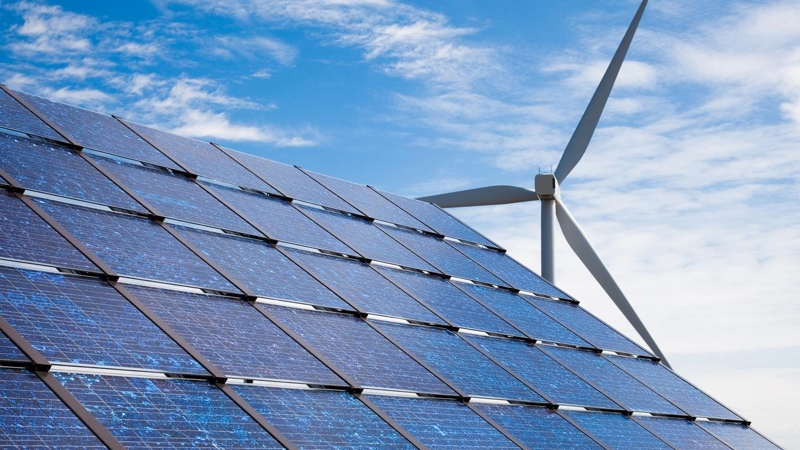 Solar panels and a wind turbine against a blue sky.