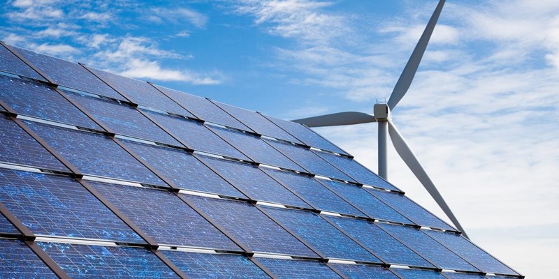 Solar panels and a wind turbine against a blue sky.