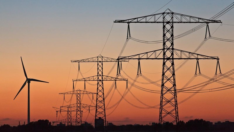 Wind turbines and electricity pylons at sunset.