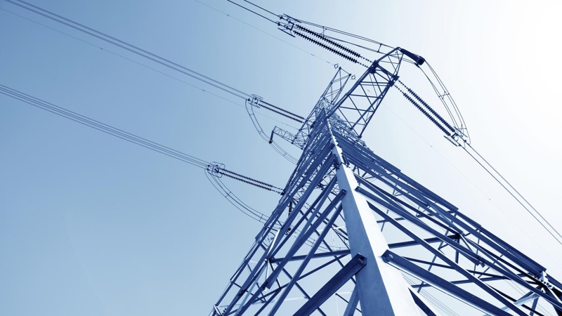 A close up of a high voltage pylon against a blue sky.