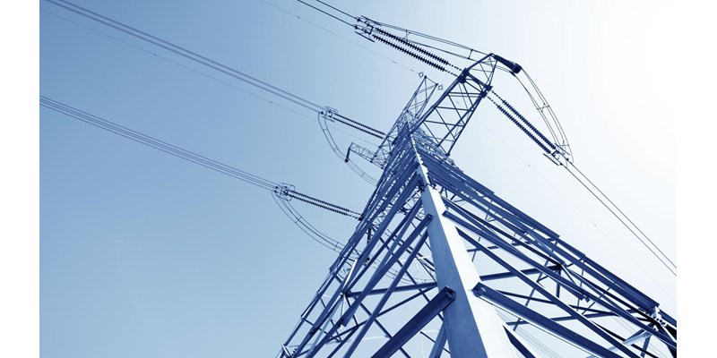 A close up of a high voltage pylon against a blue sky.