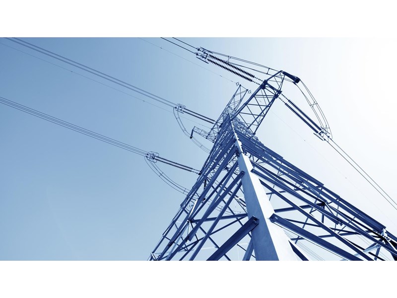 A close up of a high voltage pylon against a blue sky.