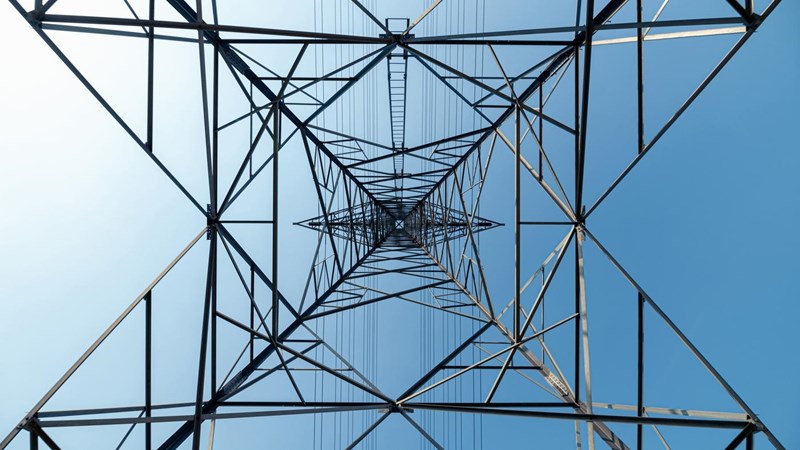 A view of the interior of a high voltage tower against a blue sky.