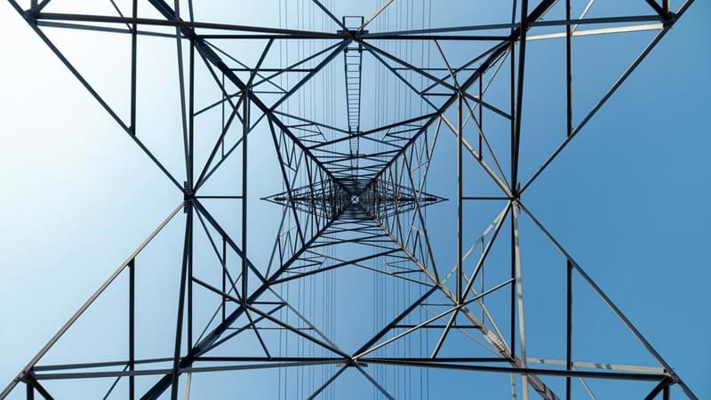 A view of the interior of a high voltage tower against a blue sky.