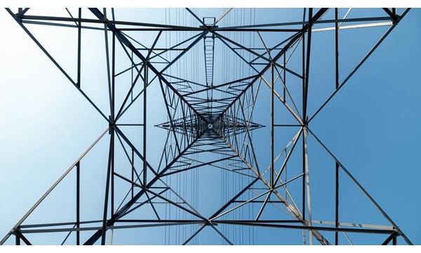 A view of the interior of a high voltage tower against a blue sky.