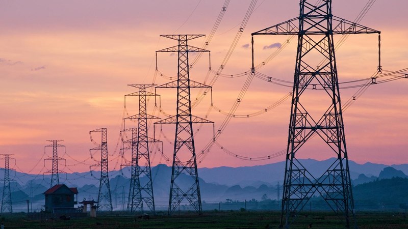 Electricity pylons at sunset, mountains are visible on the horizon.