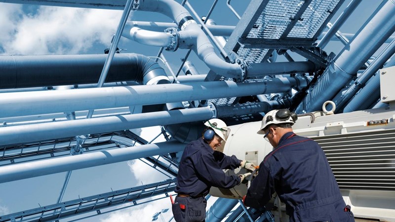 Two oil and gas workers with large fuel pipelines.