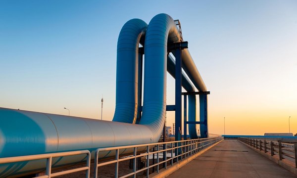 Blue pipes going to oil refinery from a port, during sunrise.