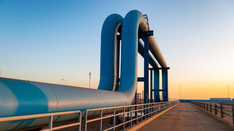 Blue pipes going to oil refinery from a port, during sunrise.